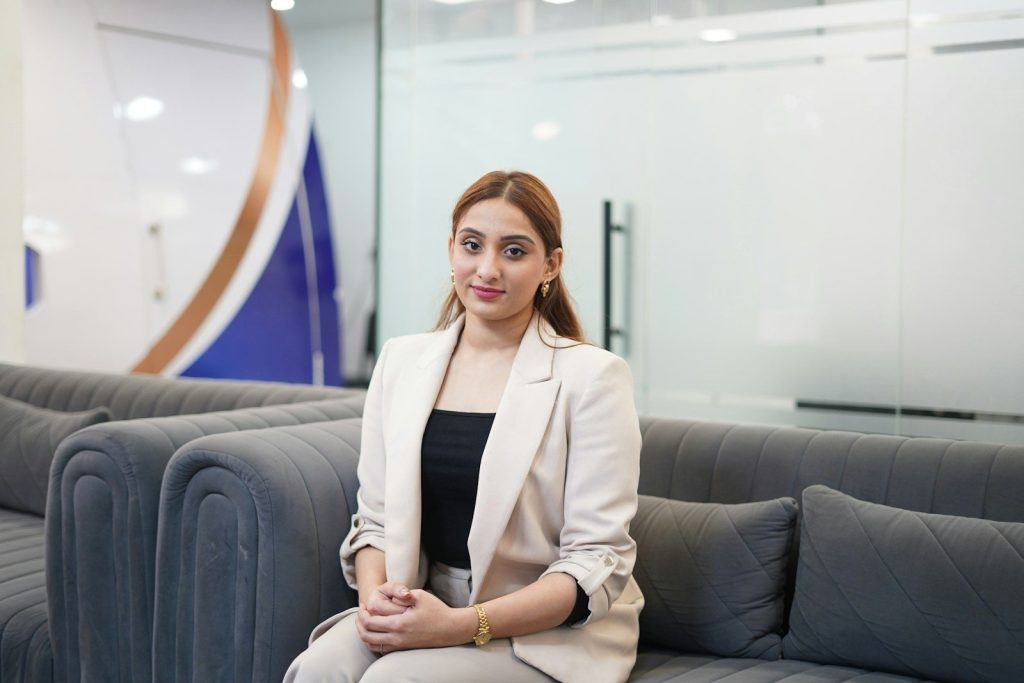 A woman in a blazer sits on a couch.